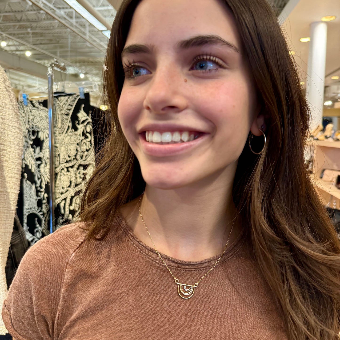 Woman smiling in a store with clothing racks in the background
