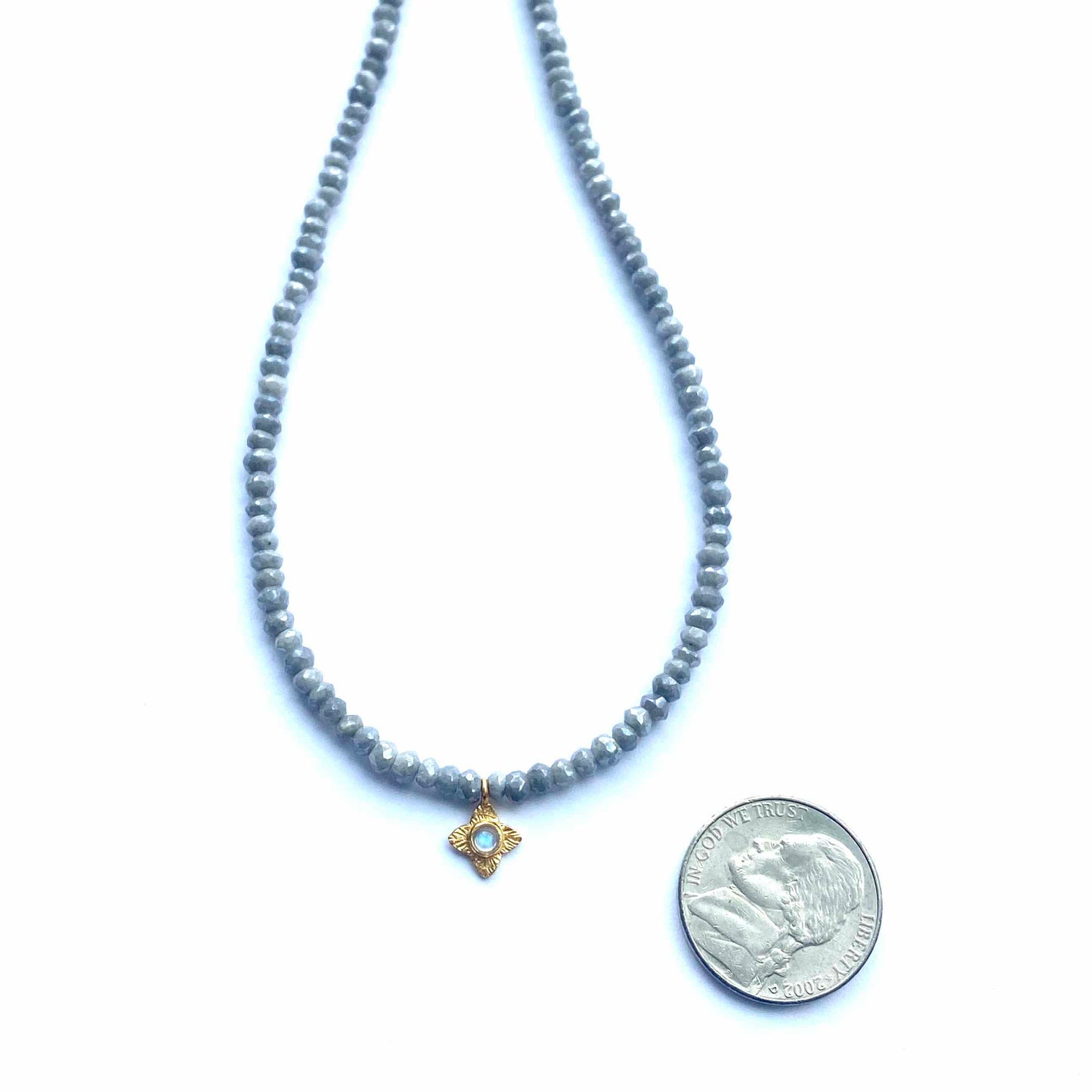 Gray beaded necklace with a gold pendant on a white background
