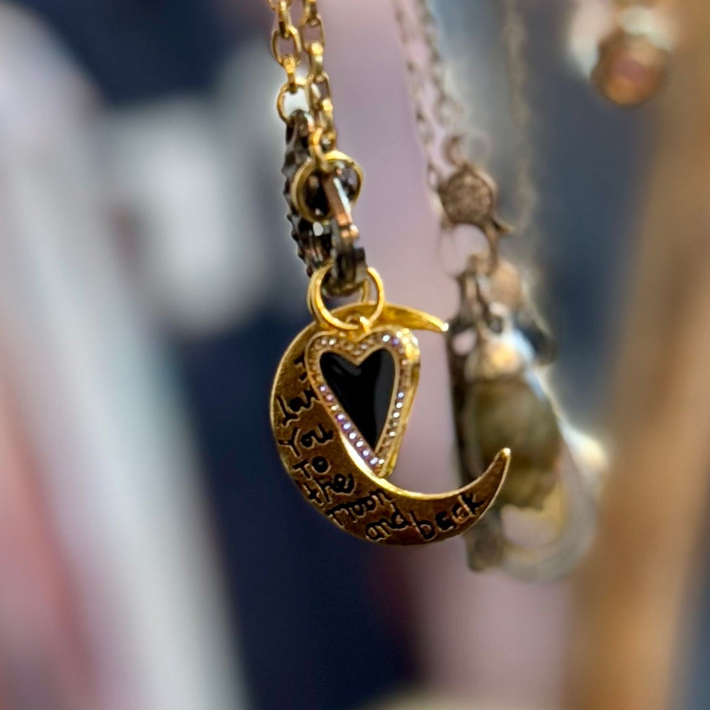 Necklace with heart and crescent moon pendant on a blurred background