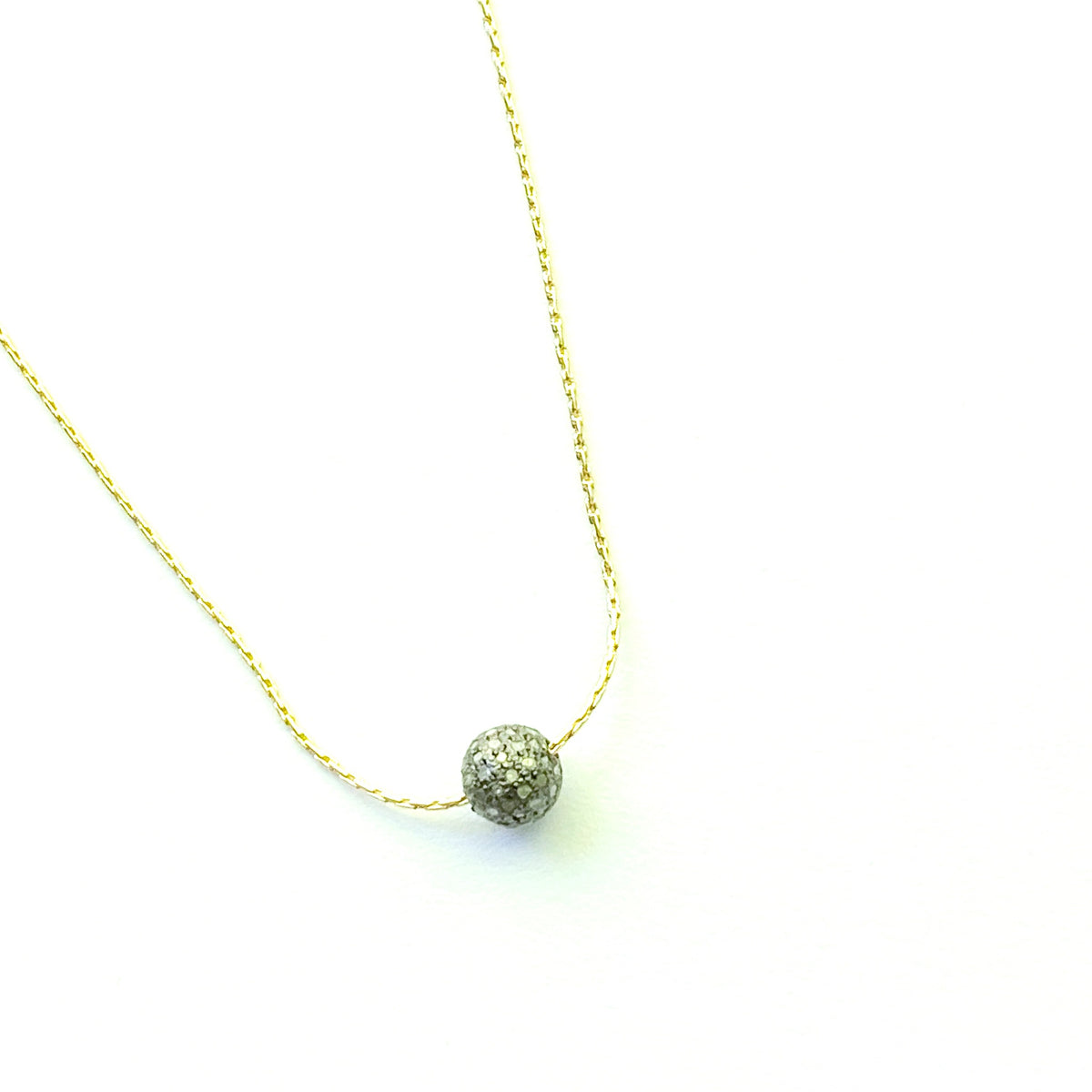 Gold necklace with a small diamond bead pendant on a white background