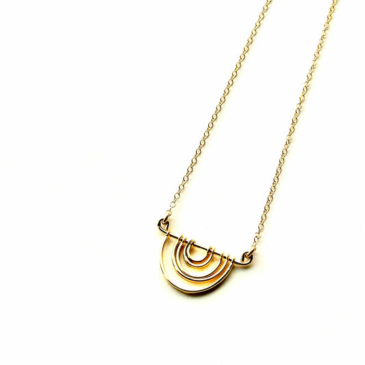 Gold necklace with a semi-circular pendant on a white background