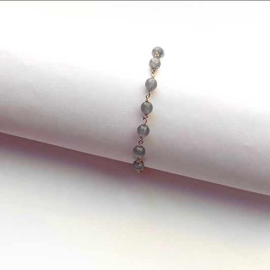 A beaded chain bracelet with round gray-blue beads and gold-tone links