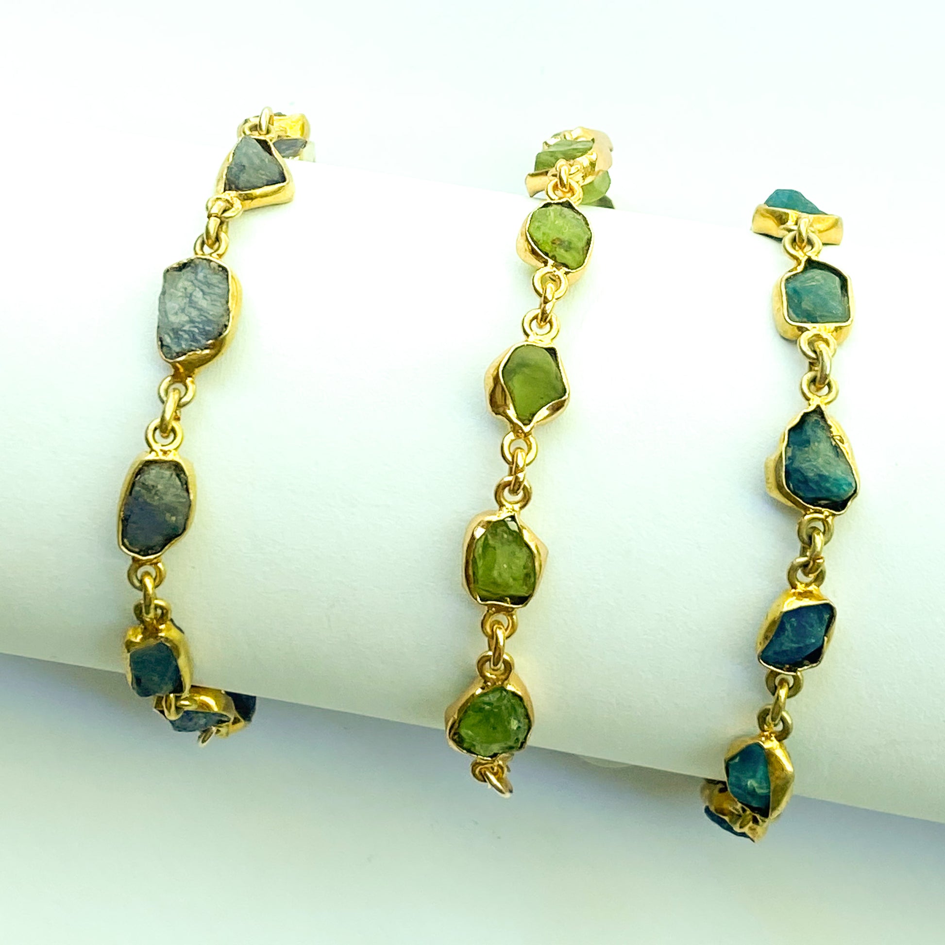 Gold earrings with green gemstones on a white background