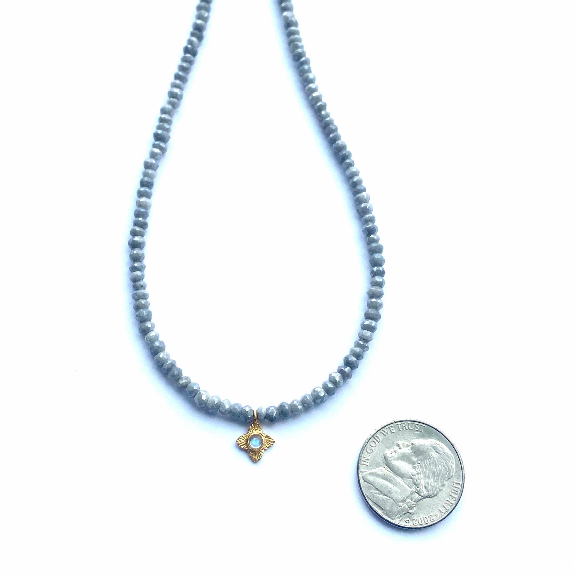 Gray beaded necklace with a gold pendant on a white background
