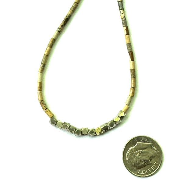 Necklace with beaded design next to a quarter for scale on a white background