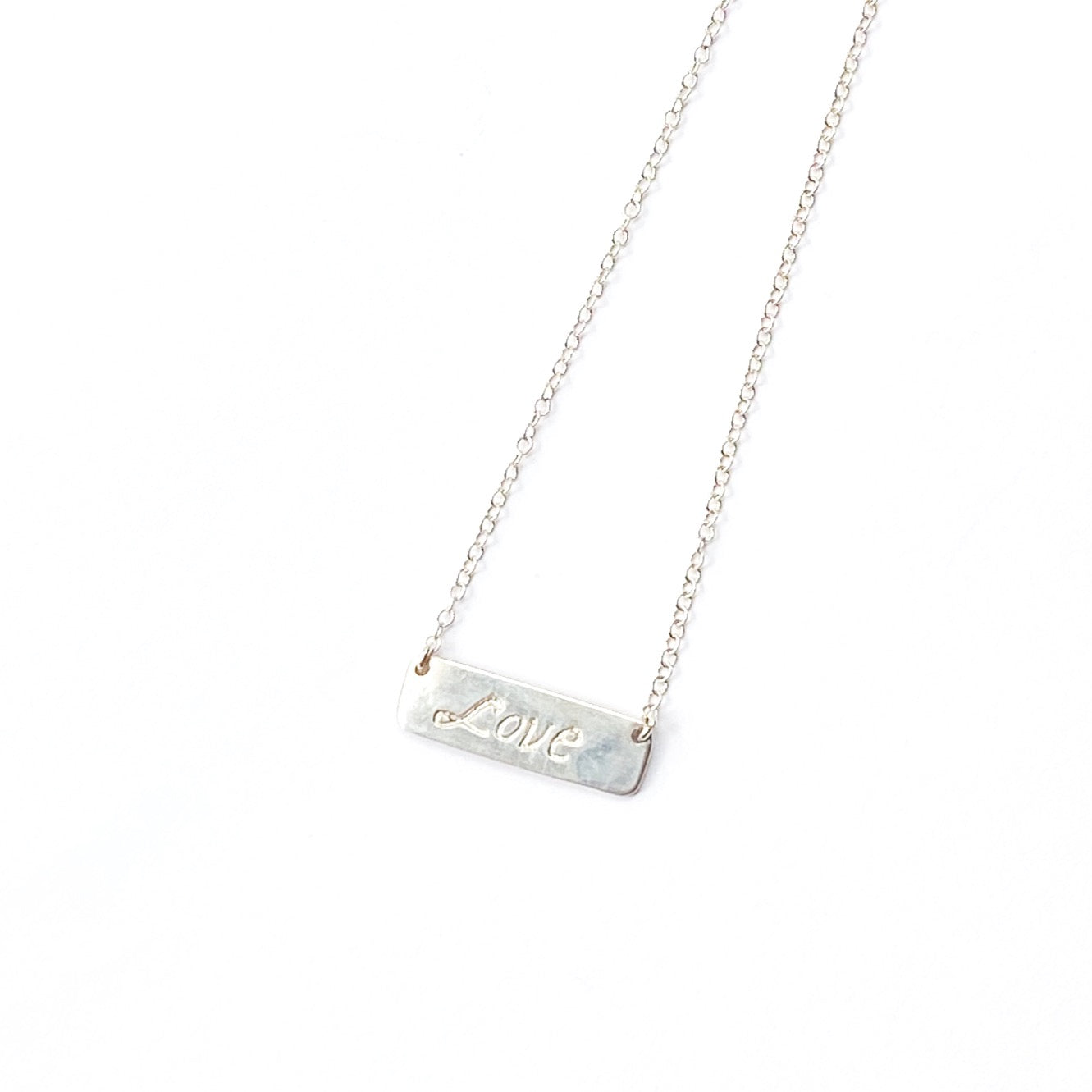 Silver necklace with a bar pendant engraved with 'LOVE' on a white background