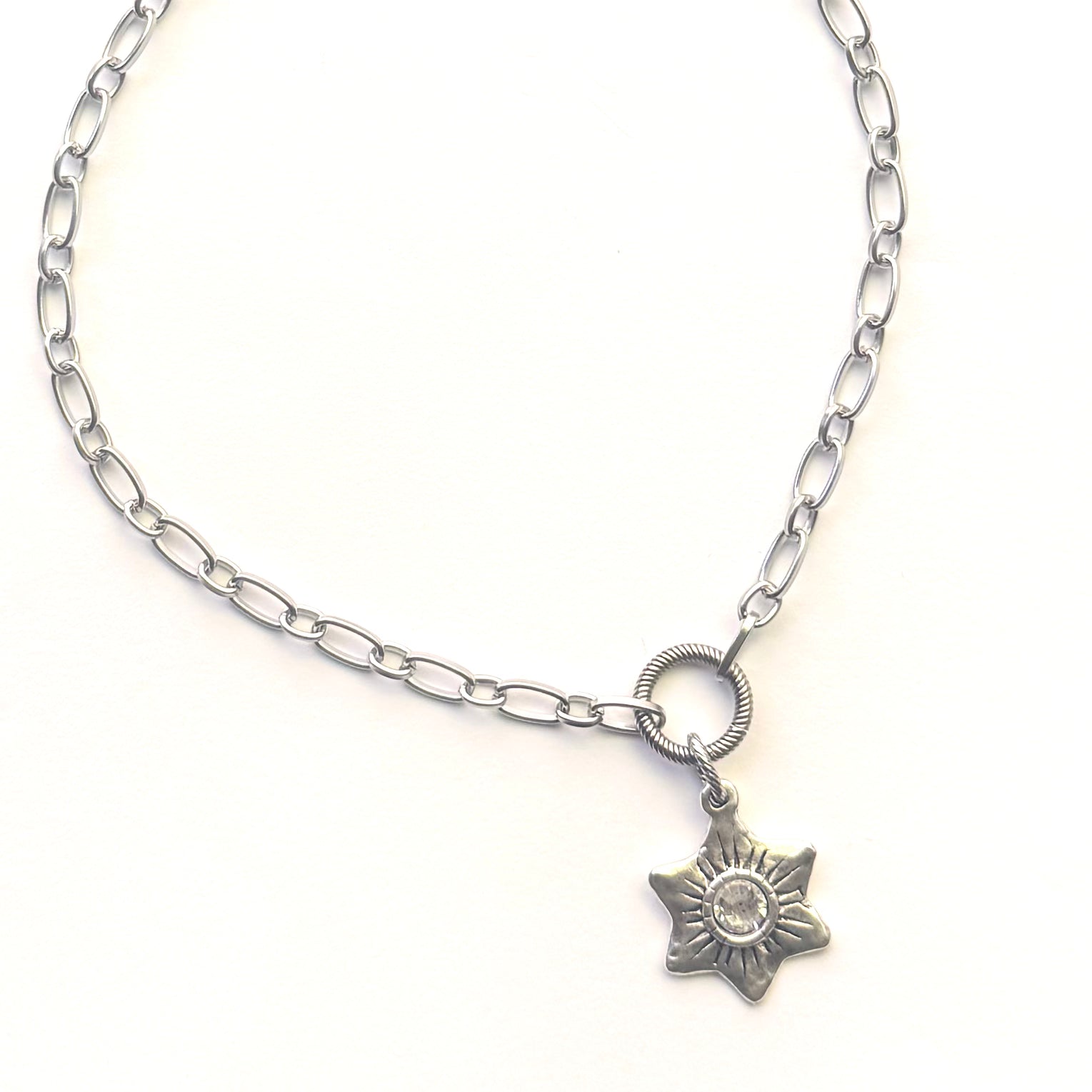 A silver-toned chain necklace featuring a small six-pointed star pendant with a clear rhinestone in the center, displayed on a clean white background.
