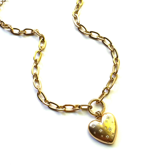 Gold toned necklace with heart pendent embellished by small crystals held together by a circle accent. 
