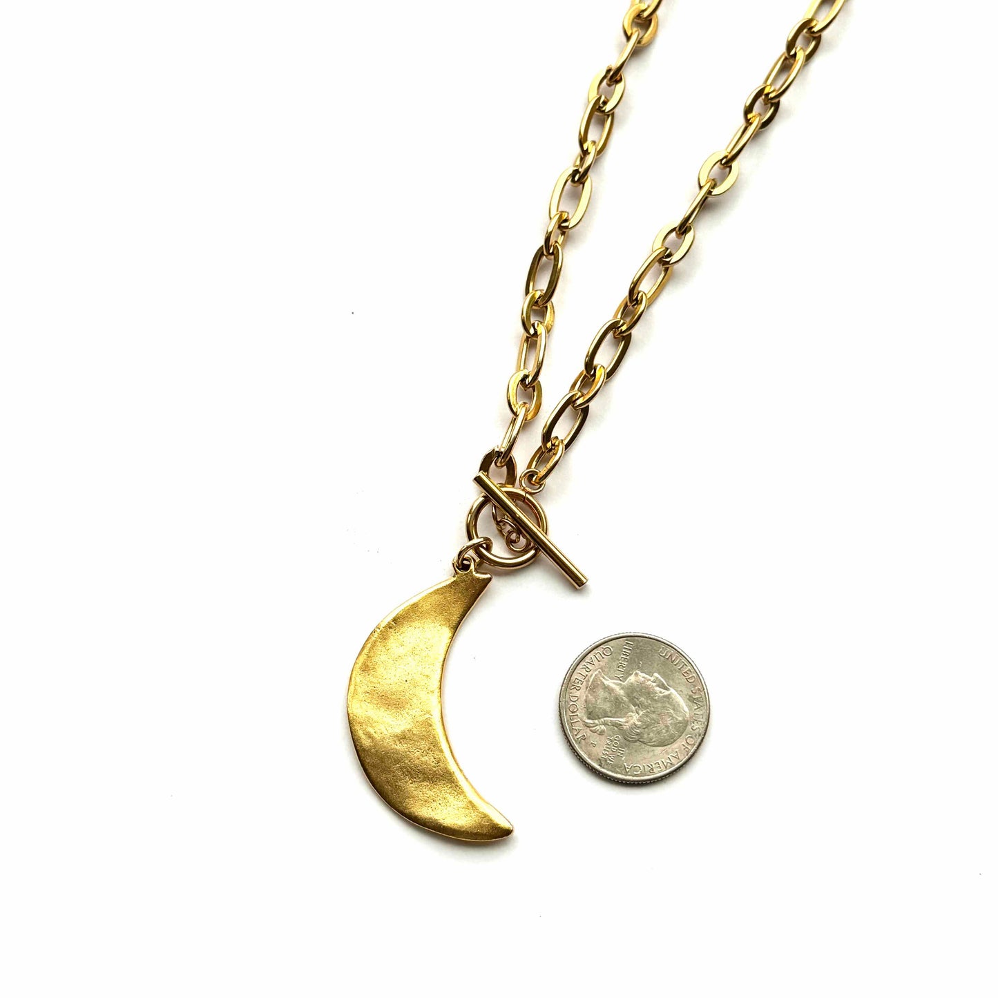 Gold necklace with a crescent moon pendant and a coin charm on a white background