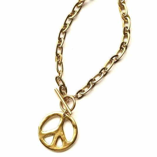 Gold chain necklace with a peace symbol pendant on a white background