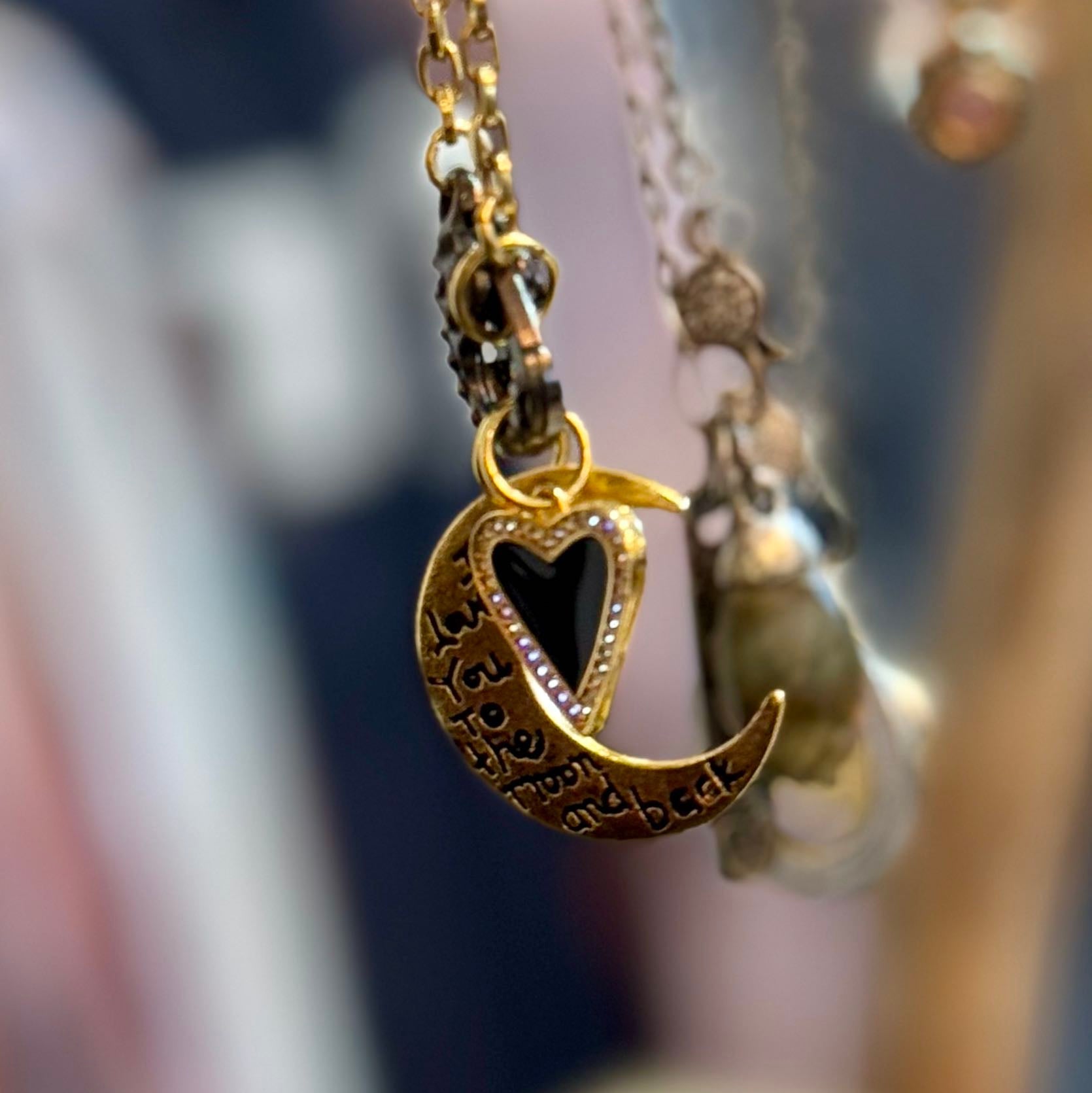 Necklace with heart and crescent moon pendant on a blurred background