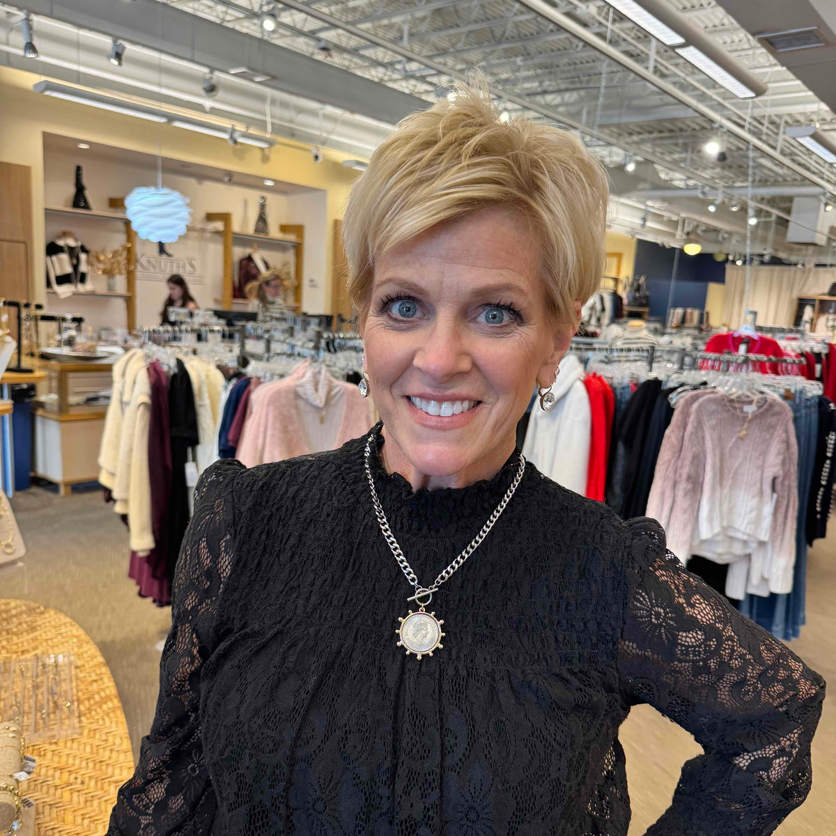 Woman in a black lace top with a necklace in a clothing store.