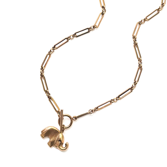 A gold paperclip chain necklace with a small elephant charm, photographed on a clean white background.