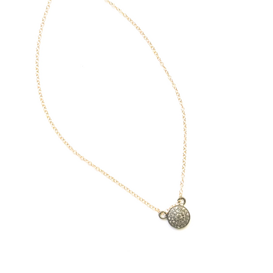 A delicate gold chain necklace featuring a small round pendant encrusted with clear stones, displayed against a solid white background.