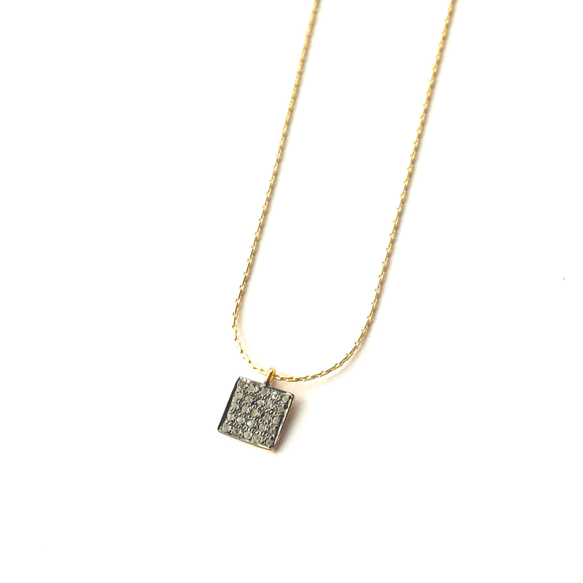 Gold necklace with a square pendant on a white background