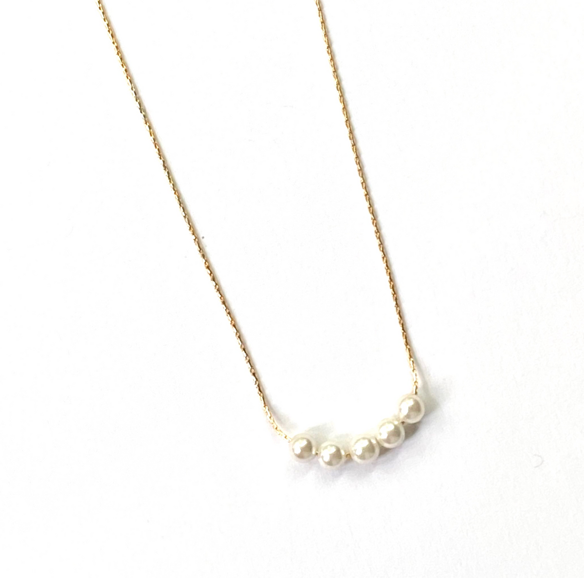 Pearl necklace on a thin chain against a white background