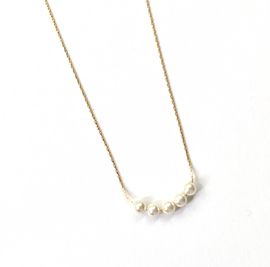 Pearl necklace on a thin chain against a white background