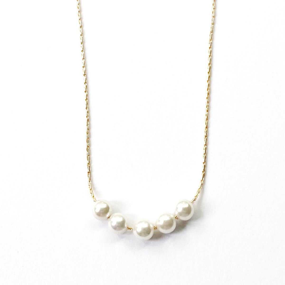 Pearl necklace on a gold chain against a white background