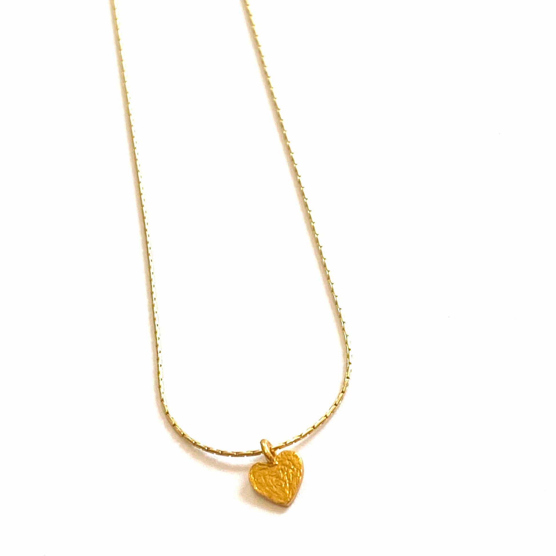 Gold necklace with a heart-shaped pendant on a white background
