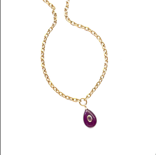A gold chain necklace featuring a small purple teardrop-shaped pendant with a central silver oval detail, displayed on a clean white background.