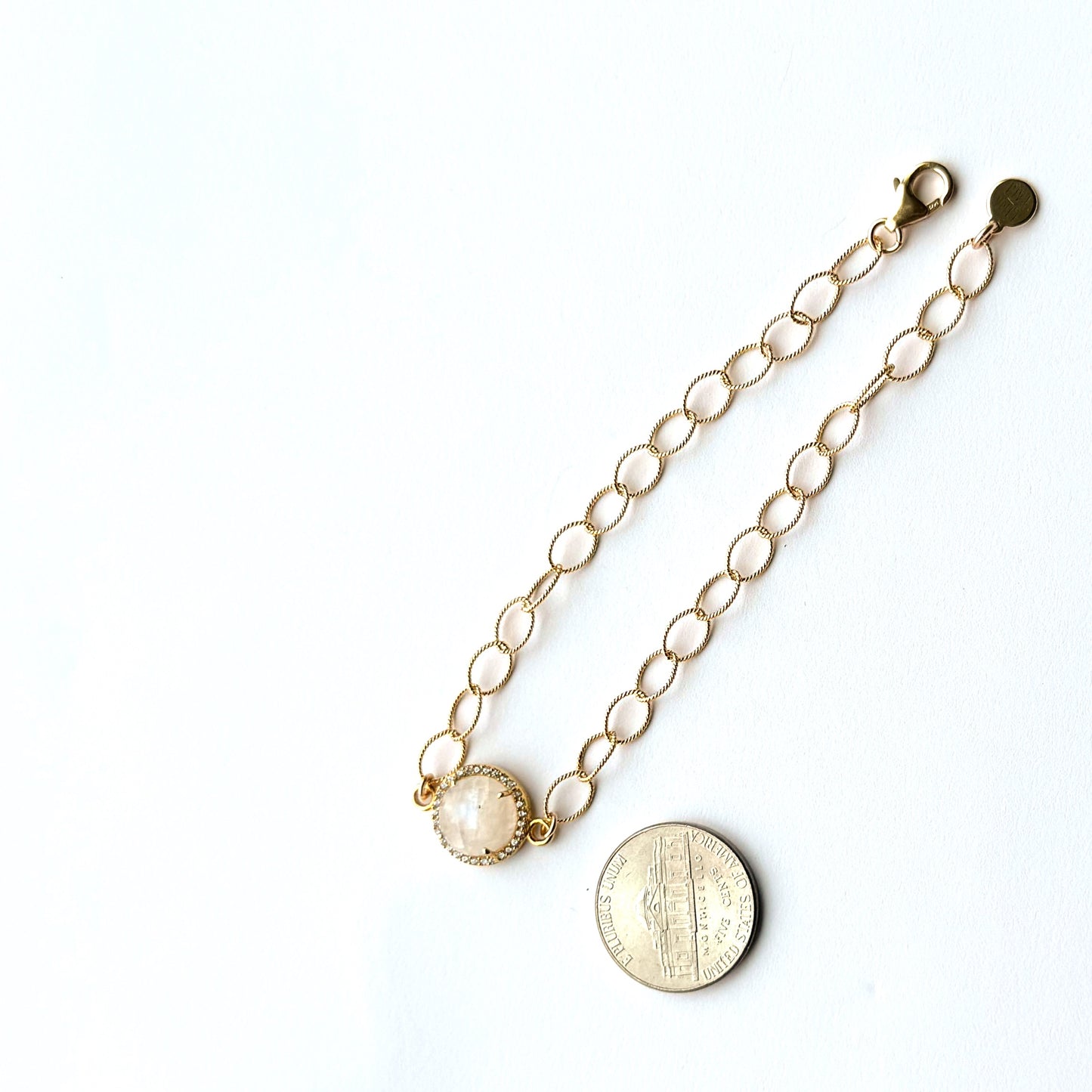 Gold chain bracelet with round pendants on a white background
