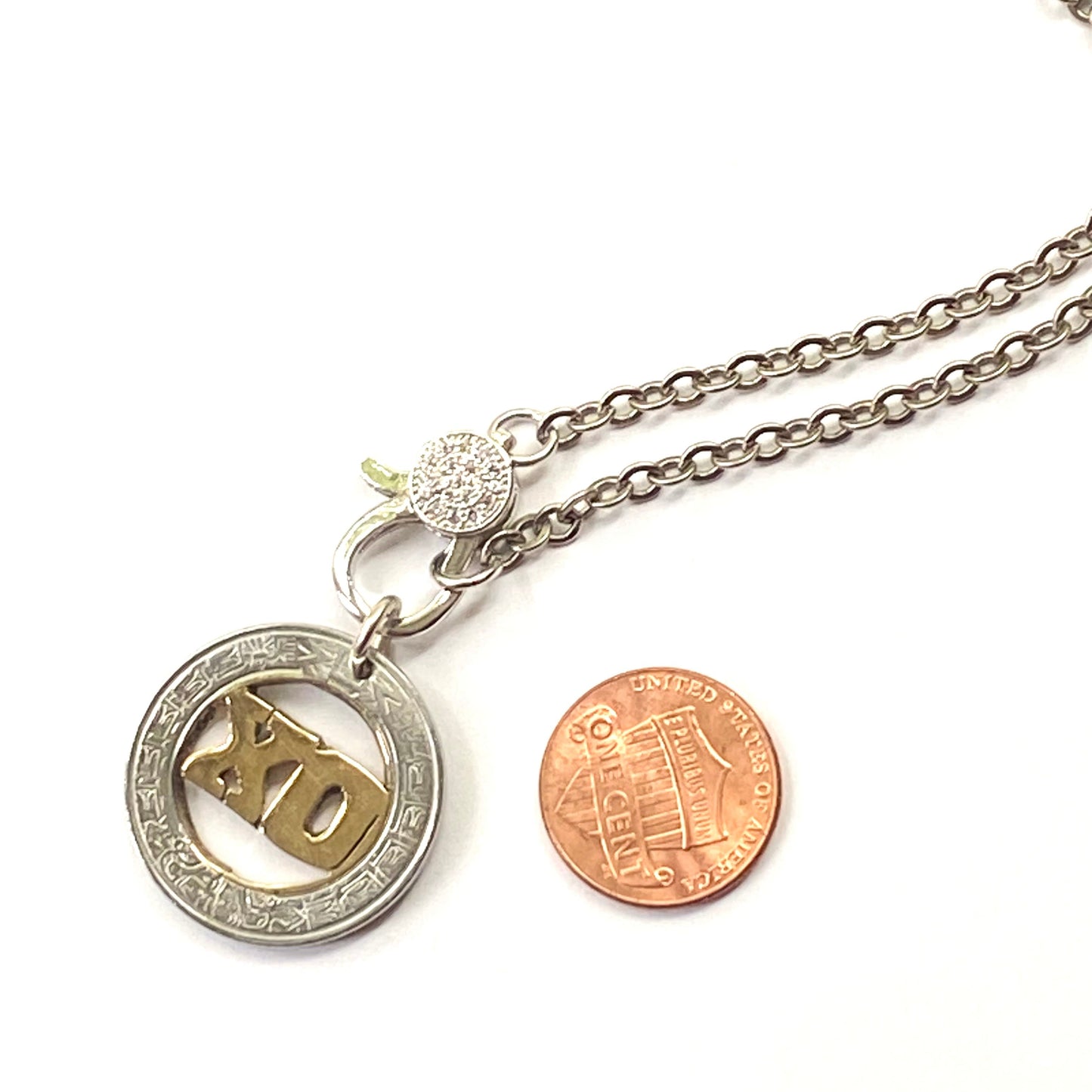 Necklace with a pendant next to a penny on a white background