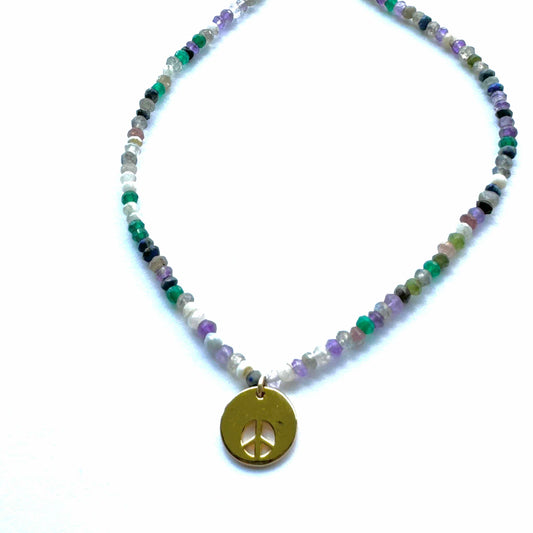 Necklace with multicolored beads and a gold peace symbol pendant on a white background